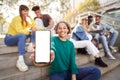 Smily girl showing smartphone with empty screen at street city with friends Mockup copy space banner Royalty Free Stock Photo