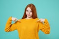 Smirked young redhead woman girl in yellow sweater posing isolated on blue turquoise wall background studio portrait Royalty Free Stock Photo