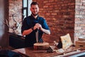 Smirking cook holds knife and posing near a table with exclusive jerky meat in a kitchen with loft interior. Royalty Free Stock Photo