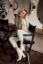 Smirking and cute woman sitting in a make up studio on a tall chair in front of round mirrors