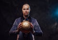 Businessman in custom dark suit poses with golden ball Royalty Free Stock Photo