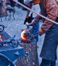 The smith is working on the horseshoe on a small forge furnace