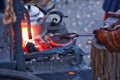 The smith is working on the horseshoe on a small forge furnace