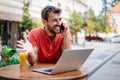 Smliling man talking on a phone while sitting in front of a laptop in cafe Royalty Free Stock Photo