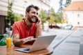 Smliling man talking on a phone while sitting in front of a laptop in cafe Royalty Free Stock Photo