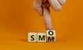 SMM vs SMO symbol. Businessman turns a cube and changes words `SMM, social media marketing` to `SMO, social media optimization Royalty Free Stock Photo