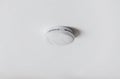 Smoke alarm, sensor or detector on white ceiling Royalty Free Stock Photo