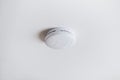 Smoke alarm, sensor or detector on white ceiling Royalty Free Stock Photo