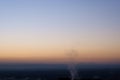 Smoke from a chimney rising in front of a colourful sunrise view