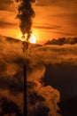 Smoke from chimny and colorful sky with sun and mountains at background Royalty Free Stock Photo