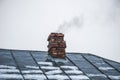 Smoke comes from the chimney of the house with a tin roof in winter Royalty Free Stock Photo