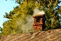 Smoke coming out of an old brick chimney on a historic roof Royalty Free Stock Photo