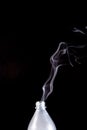 Smoke coming out of a plastic bottle against a black background Royalty Free Stock Photo