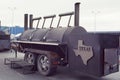 Smoke coming out of a smokestack of a small black smoker grill or barbecue. film photo