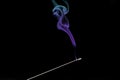 Smoke curls from burning incense stick for relaxation and meditation black background