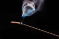 Smoke curls from burning incense stick for relaxation and meditation black background
