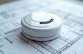 Smoke detector on architectural blueprint. Safety equipment for fire prevention. Device for home security. Alarm system Royalty Free Stock Photo