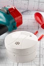 Smoke detector or fire alarm sensor on white architectural plans background with drill and screwdriver, house safety or security Royalty Free Stock Photo
