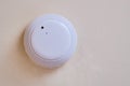 Smoke detector of fire alarm, the white background of the wall. Sensor on beige ceiling. Smoke fire alarm in the inactive state