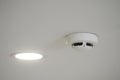 Smoke detector installed on ceiling with ceiling light Royalty Free Stock Photo