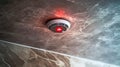 Smoke detector installed on the ceiling, signaling alert with a red light in a modern interior design Royalty Free Stock Photo