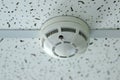 Smoke detector mounted on plain ceiling, fire alarm system. Royalty Free Stock Photo