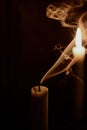 Smoke from an extinguished candle against the light of another lit candle on a black background