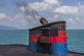 Smoke from ferry boat flue during sea with sunlight, sea water and blue sky in background, Thailand