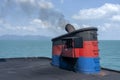 Smoke from ferry boat flue during sea with sunlight, sea water and clear sky in background, Thailand