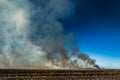 Smoke filled sky with burning farm field, wildfire