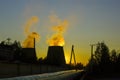 Smoke from huge pipes of city thermal power plant in sunset sky