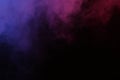 Artificial magic smoke in red-blue light on black background Royalty Free Stock Photo