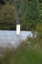 Smoke rises from the chimney on the house. Heating season. Roof with smoking chimney and trees in autumn