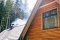 Smoke rises from a chimney on the roof of a wooden house in the forest Royalty Free Stock Photo