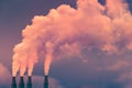 Smoke and steam rising into the air from power plant stacks; dark clouds background; concept for environmental pollution and