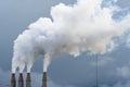 Smoke and steam rising into the air from power plant stacks; dark clouds background; concept for environmental pollution and