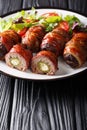 Smoked Armadillo eggs with jalapeno and cheese wrapped in bacon served with fresh salad close-up on a plate. vertical Royalty Free Stock Photo