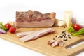 Smoked bacon slab on cutting board sliced with vegetables Royalty Free Stock Photo