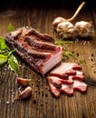 Smoked bacon, slices of smoked bacon on a wooden rustic table with addition of fresh aromatic herbs. Natural product from organic