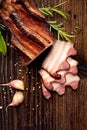 Smoked bacon on a wooden rustic table with addition of fresh aromatic herbs, top view