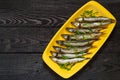 Smoked capelin with green onions on yellow plate