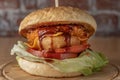 smoked chickenburger centred on wooden plate on dim wall background with bricks