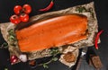 Smoked fillet salmon, red fish steak with spices and tomato on craft paper over dark stone background. Tenderloin fish still life Royalty Free Stock Photo