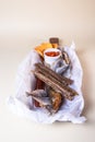 A variety of smoked fish on a wooden board with a bowl of red pepper flakes. assorted fish