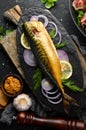 Smoked fish mackerel with onion and lemon on a black plate. Top view. Free space for your text. Royalty Free Stock Photo