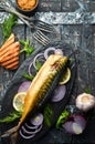 Smoked fish mackerel with onion and lemon on a black plate. Top view. Royalty Free Stock Photo