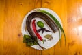 smoked garfish with lime, Basil, green onions, chili, nori chips, spices, olive oil in a white ceramic dish, on a wooden table Royalty Free Stock Photo