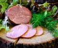 Smoked ham with dill, lettuce on wooden trunk board