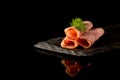 Smoked Ham with Herbs on Stone Plate Isolated on black background with reflections. copy space