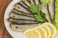 Smoked headless sprats with lemon, close-up in selective focus